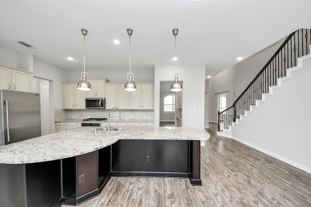 kitchen with a spacious island, visible vents, backsplash, cream cabinets, and appliances with stainless steel finishes