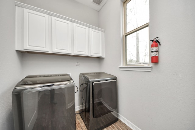 laundry area with cabinet space, visible vents, baseboards, wood finished floors, and washing machine and clothes dryer