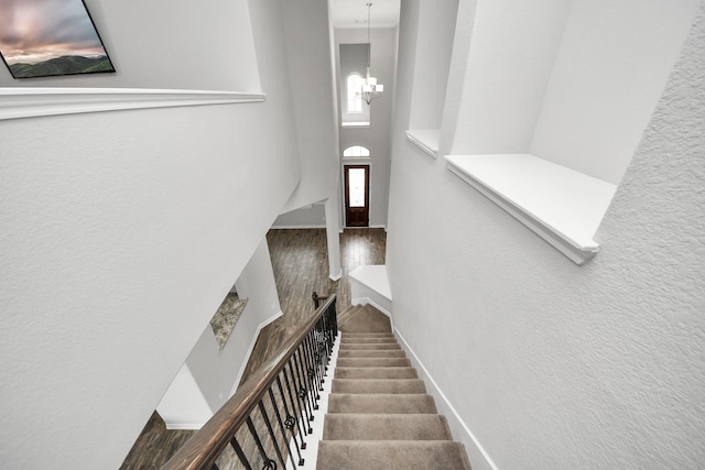 stairs with a towering ceiling, baseboards, and an inviting chandelier