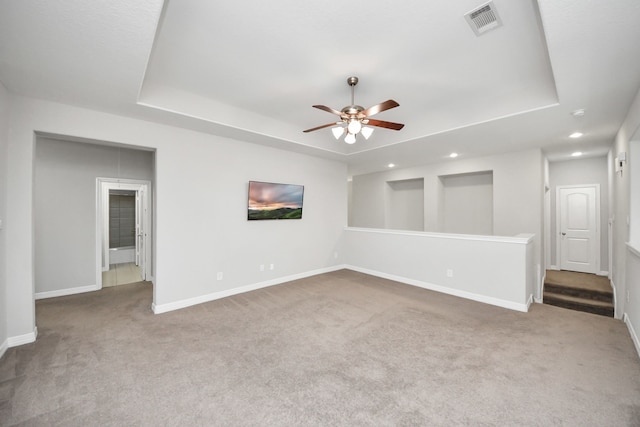 carpeted spare room with recessed lighting, a raised ceiling, visible vents, ceiling fan, and baseboards