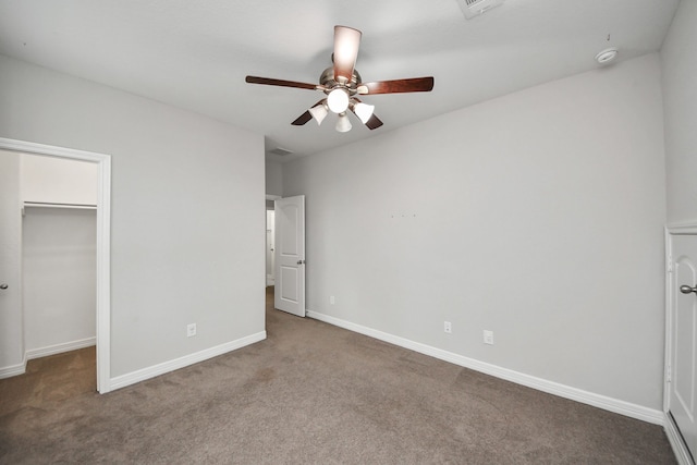 unfurnished bedroom featuring ceiling fan, carpet floors, baseboards, a closet, and a walk in closet