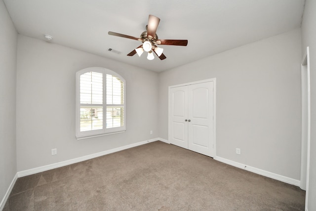 carpeted spare room with ceiling fan, visible vents, and baseboards