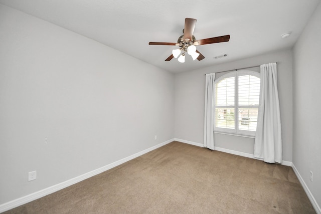 carpeted spare room featuring visible vents, baseboards, and ceiling fan