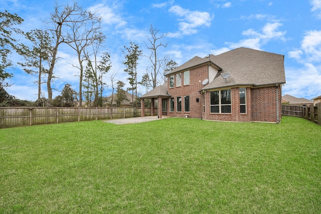 rear view of property featuring brick siding, a yard, a shingled roof, a patio area, and a fenced backyard