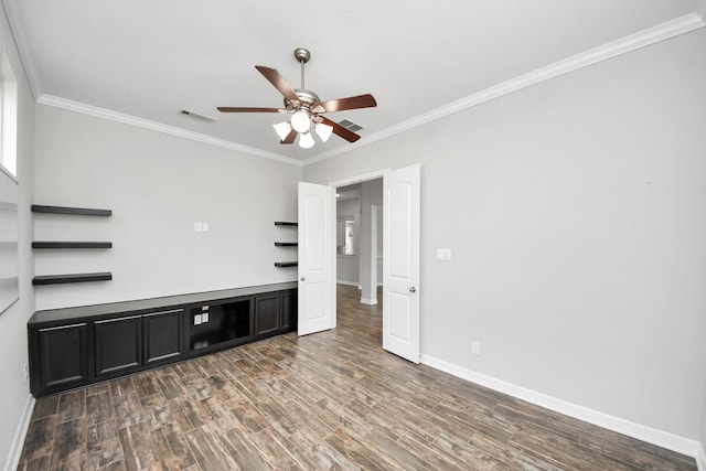 interior space featuring wood finished floors, a ceiling fan, baseboards, visible vents, and crown molding