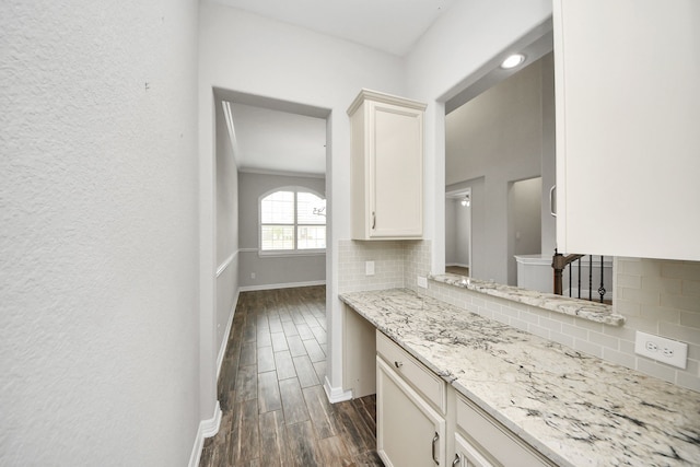 kitchen with light stone countertops, white cabinetry, baseboards, decorative backsplash, and wood tiled floor