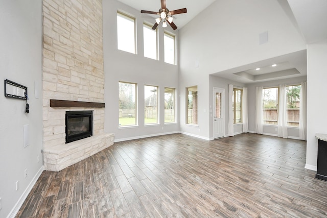 unfurnished living room with a stone fireplace, recessed lighting, wood finished floors, a ceiling fan, and baseboards