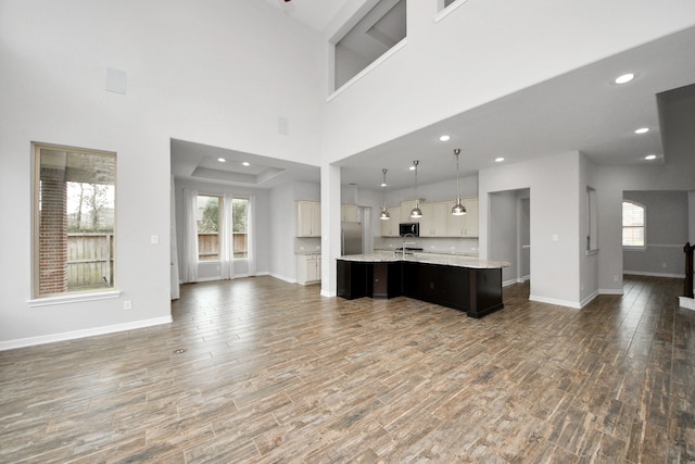 kitchen with wood finished floors, open floor plan, light countertops, appliances with stainless steel finishes, and a large island with sink