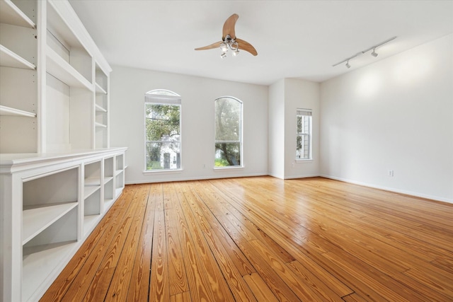 unfurnished room with hardwood / wood-style flooring, baseboards, a ceiling fan, and rail lighting