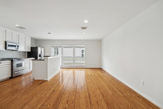 kitchen featuring appliances with stainless steel finishes, white cabinets, visible vents, and light wood-style flooring