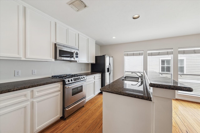 kitchen featuring appliances with stainless steel finishes, a sink, visible vents, and light wood-style floors