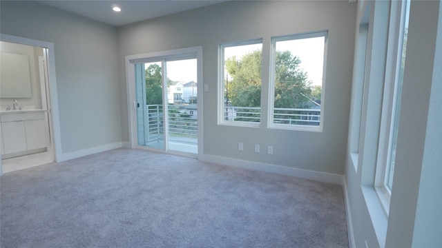 spare room with recessed lighting, light colored carpet, a sink, and baseboards