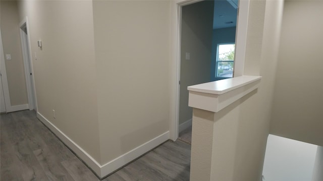 corridor featuring light wood-type flooring and baseboards