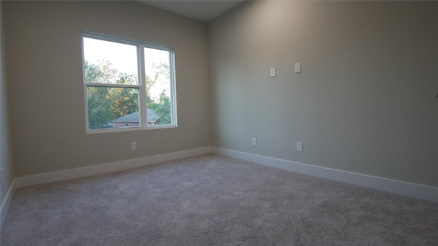 spare room featuring light carpet and baseboards