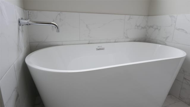 full bathroom featuring marble finish floor and a soaking tub