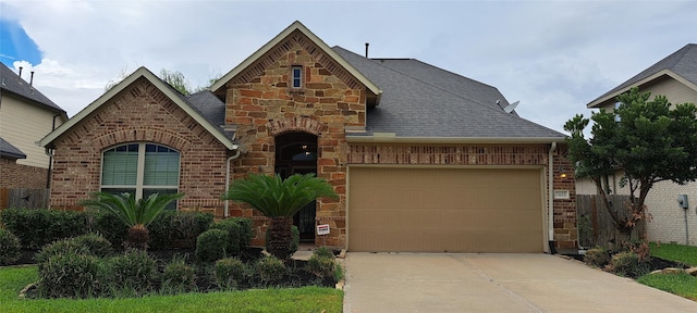 tudor-style house featuring concrete driveway, brick siding, an attached garage, and stone siding