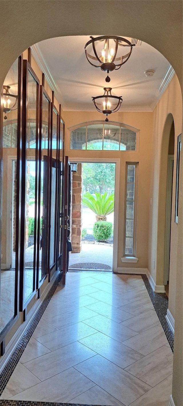doorway featuring arched walkways, ornamental molding, and a wealth of natural light