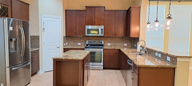 kitchen with decorative backsplash, appliances with stainless steel finishes, light stone counters, a center island, and a sink