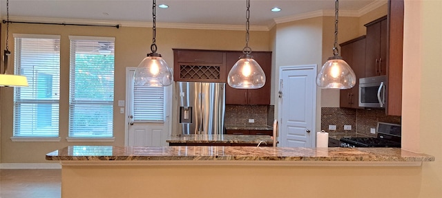 kitchen with pendant lighting, stainless steel appliances, a wealth of natural light, decorative backsplash, and ornamental molding
