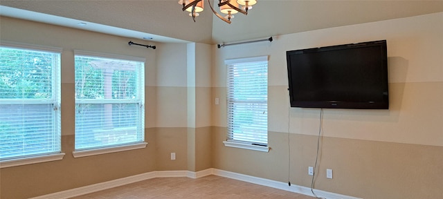 empty room featuring a chandelier, plenty of natural light, wood finished floors, and baseboards