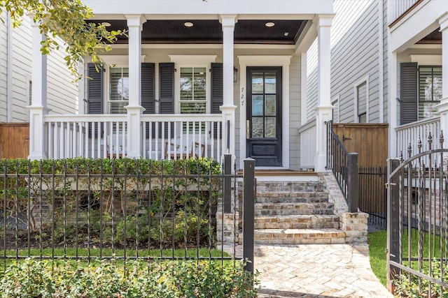 entrance to property with covered porch and fence