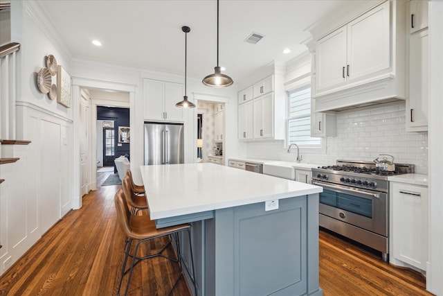 kitchen featuring visible vents, premium appliances, a breakfast bar, a center island, and a sink