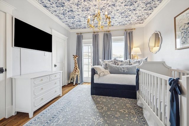 bedroom with an inviting chandelier, wood finished floors, and crown molding