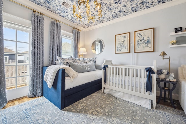 bedroom featuring a notable chandelier, visible vents, crown molding, and wood finished floors