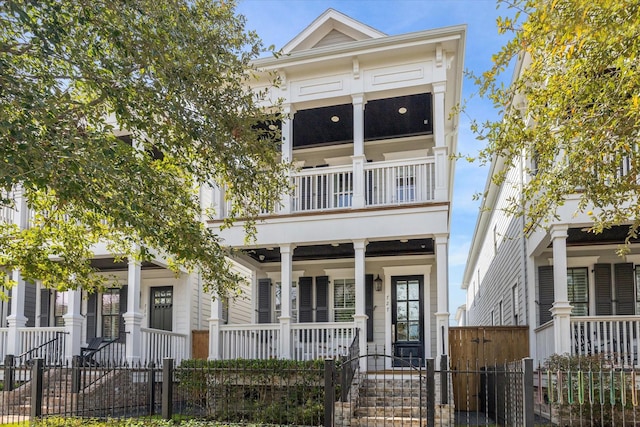 view of front of property with a porch, a fenced front yard, a balcony, and a gate