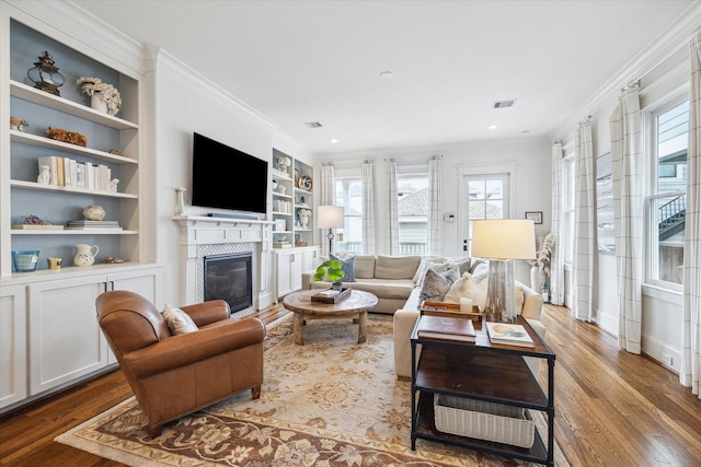 living room with ornamental molding, plenty of natural light, wood finished floors, and visible vents