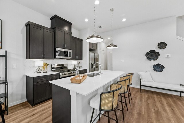 2110 Dewalt St Unit H, Houston, TX 77088 - kitchen with appliances with stainless steel finishes, a sink, a breakfast bar, light wood-style flooring, and recessed lighting