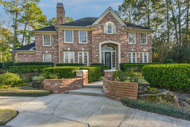 view of front of house featuring a chimney and brick siding