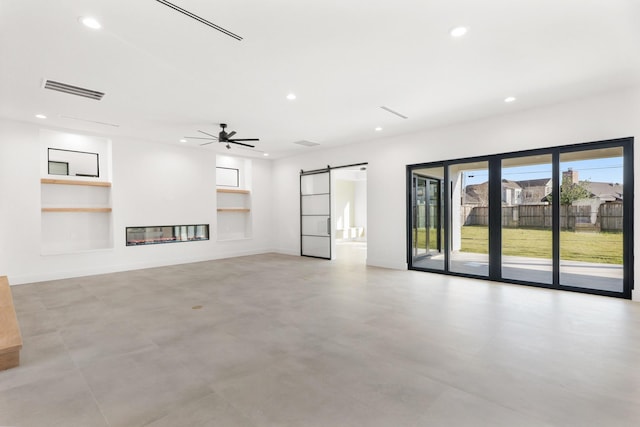 unfurnished living room with recessed lighting, visible vents, a barn door, a glass covered fireplace, and baseboards