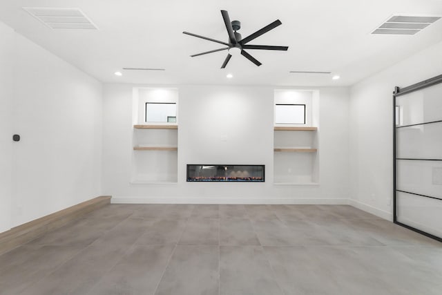 unfurnished living room featuring a barn door, visible vents, built in features, and a glass covered fireplace