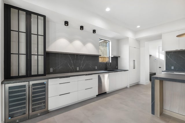 kitchen with dark countertops, a sink, stainless steel dishwasher, and modern cabinets