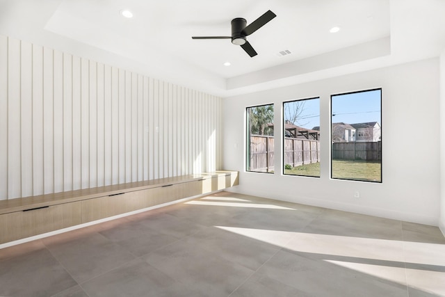 empty room with ceiling fan, a raised ceiling, visible vents, and recessed lighting