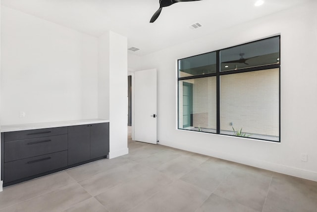 spare room featuring ceiling fan, visible vents, and baseboards