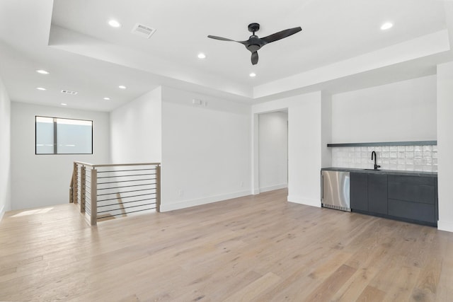 bar featuring light wood finished floors, tasteful backsplash, recessed lighting, visible vents, and a sink