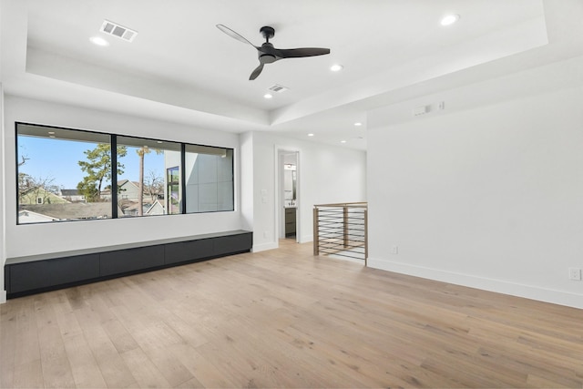 spare room featuring light wood-type flooring, a raised ceiling, and visible vents