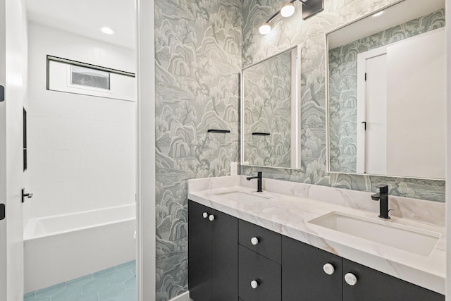 full bath featuring double vanity, wallpapered walls, a washtub, and a sink