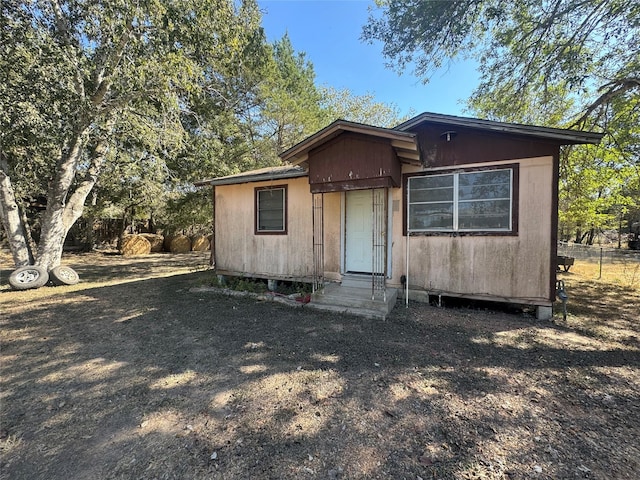 rear view of property featuring entry steps and fence