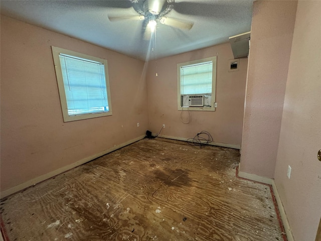 empty room with a healthy amount of sunlight, ceiling fan, baseboards, and cooling unit