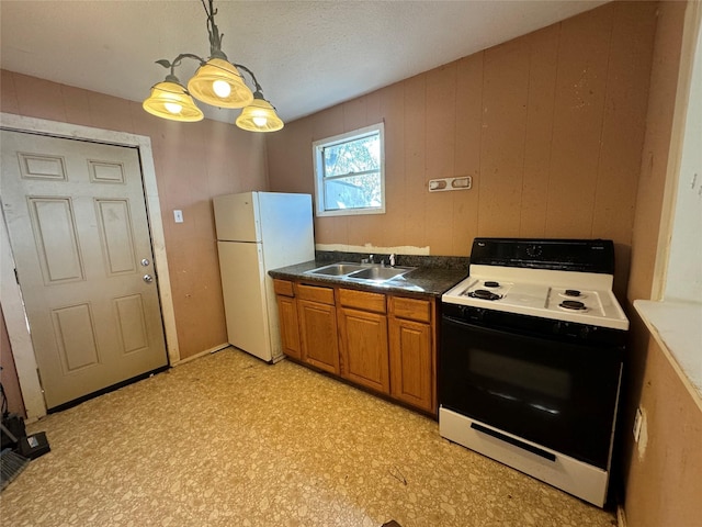 kitchen featuring brown cabinets, light floors, freestanding refrigerator, a sink, and range with electric cooktop