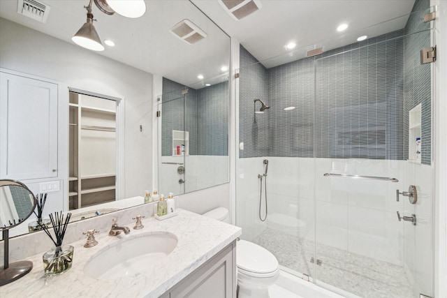 full bath featuring visible vents, toilet, vanity, a shower stall, and recessed lighting