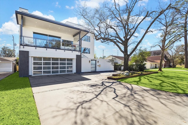 view of front of home with driveway, a balcony, a front lawn, and stucco siding