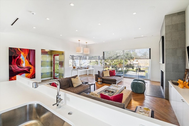 kitchen with recessed lighting, light countertops, white cabinets, a sink, and wood finished floors