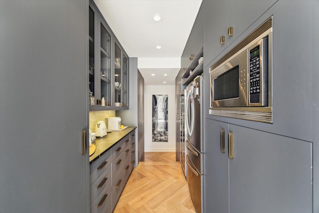 kitchen featuring tasteful backsplash, glass insert cabinets, appliances with stainless steel finishes, gray cabinets, and recessed lighting