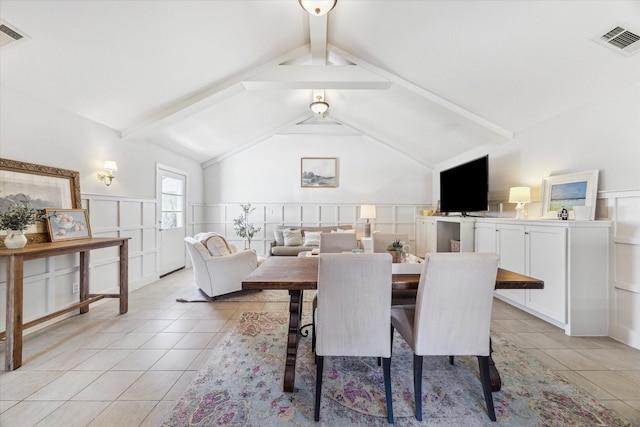 dining area featuring a wainscoted wall, visible vents, vaulted ceiling with beams, and light tile patterned flooring