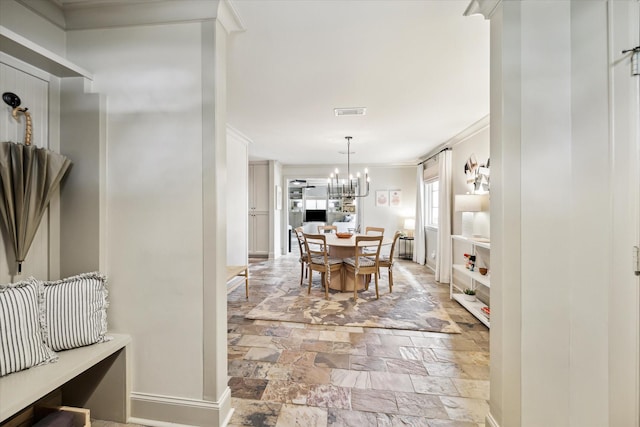 dining area with visible vents, stone finish floor, a chandelier, and baseboards