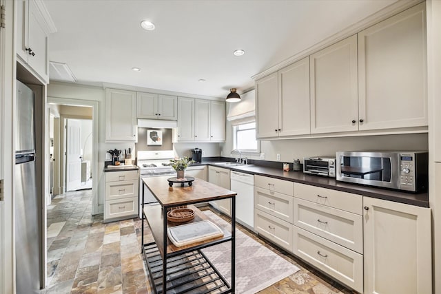 kitchen with recessed lighting, stainless steel appliances, a sink, stone finish floor, and dark countertops